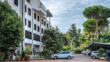 Un hôtel à plusieurs étages doté d’un parking, entouré d’arbres et de plantes en pot.