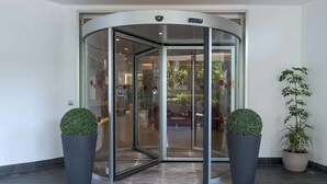 A revolving door with glass panels and two potted plants on either side. - Hotel La Giocca (Rome)