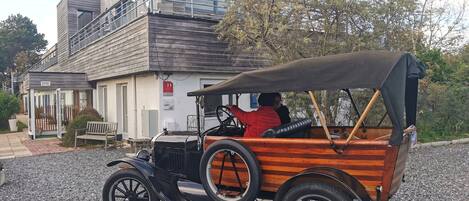 A vintage car parked in front of a building with a sign that reads "ARGOUSIERS".