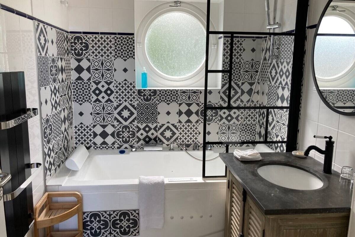 A bathroom with a bathtub, a sink, and a mirror.