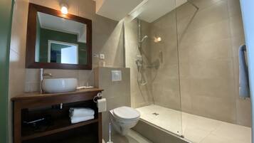 A modern bathroom with a glass-enclosed shower, a bathtub, and a sink with a mirror above it.