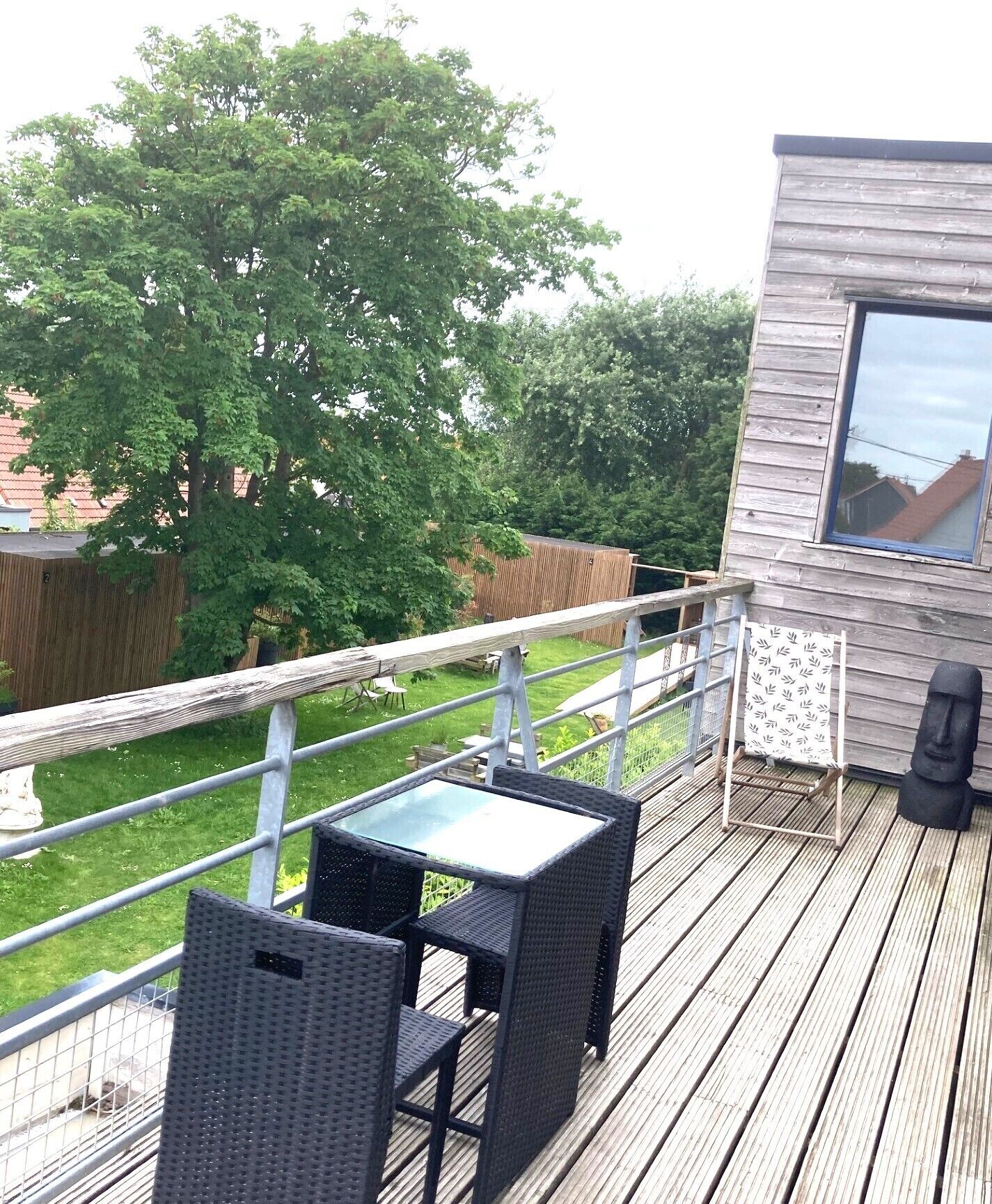 A wooden deck with outdoor furniture, a small table, and a seating area.