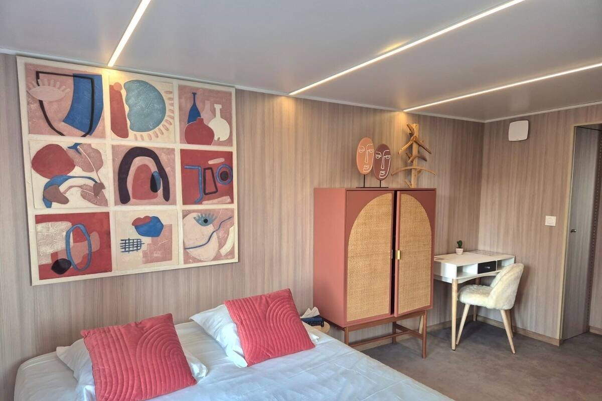 A modern hotel room with a large bed, a desk, and a cabinet.