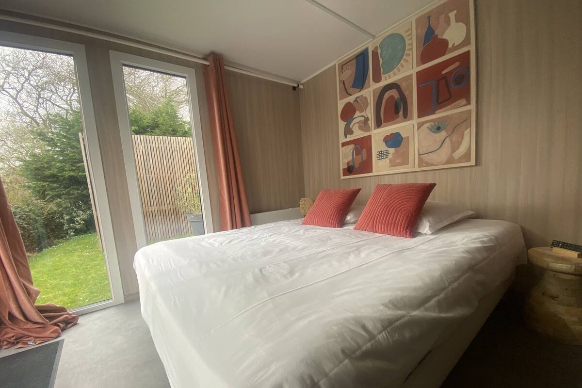 A bedroom with a large bed, a sliding glass door to a balcony, and a wall with abstract art.