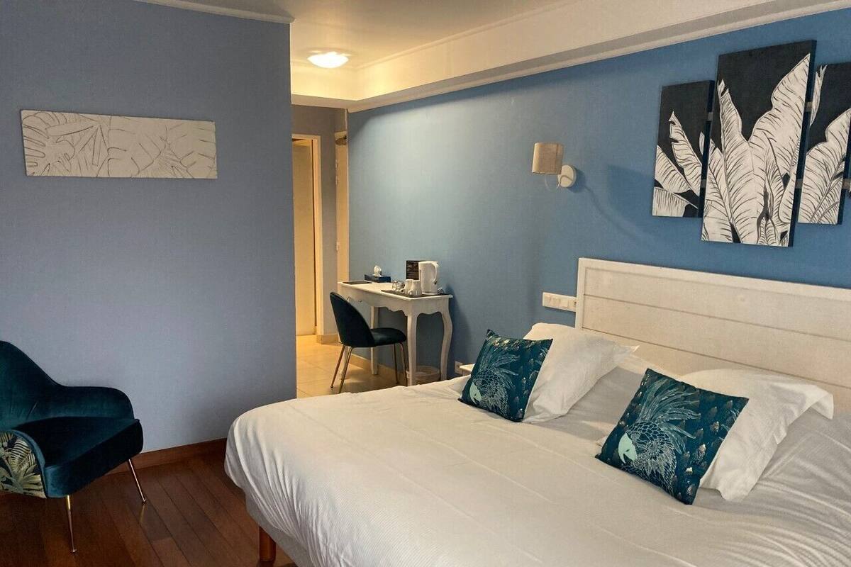 A hotel room with a large bed, a desk, and a chair.