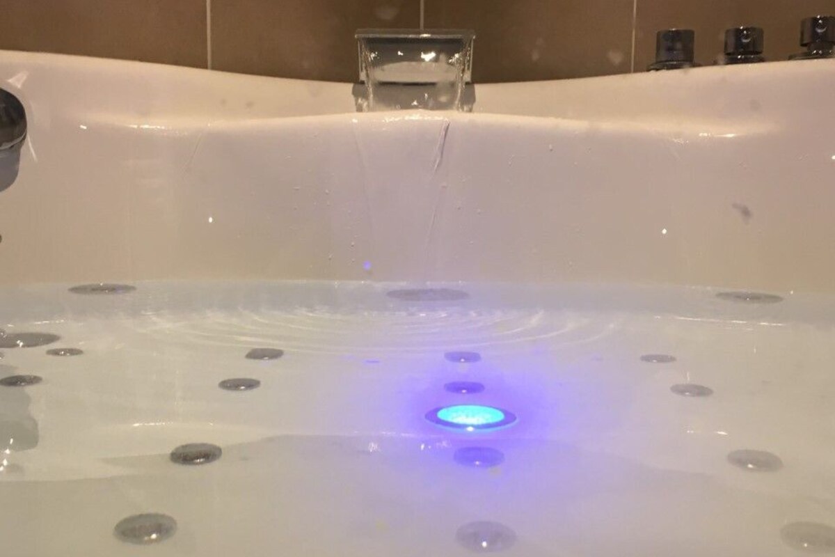 A hot tub with a central blue light and multiple jets.