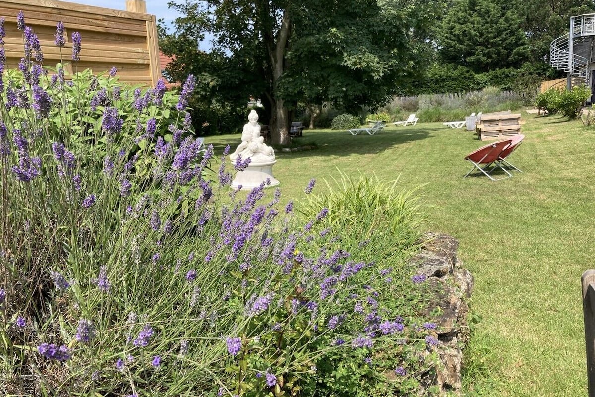A garden with lavender plants, a white statue, and outdoor seating.