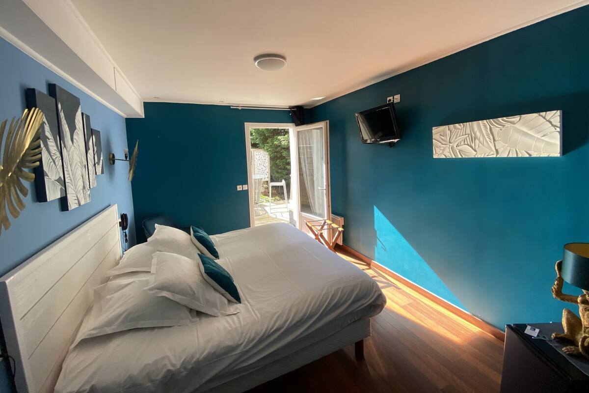 A bedroom with a bed, a TV, and a view of the outdoors.