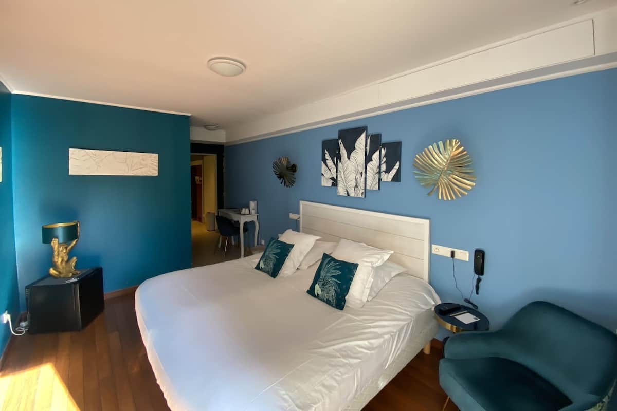 A bedroom with a large bed, a desk, and a chair.