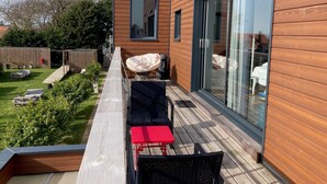 A modern outdoor deck with a wooden deck, a red table, and two black chairs. - Hôtel des Argousiers (Ambleteuse)