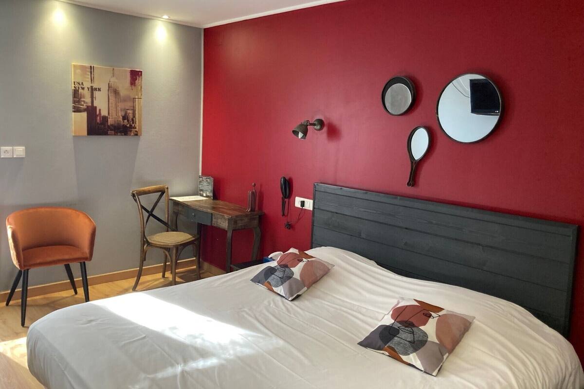 A hotel room with a bed, a desk, and a chair.