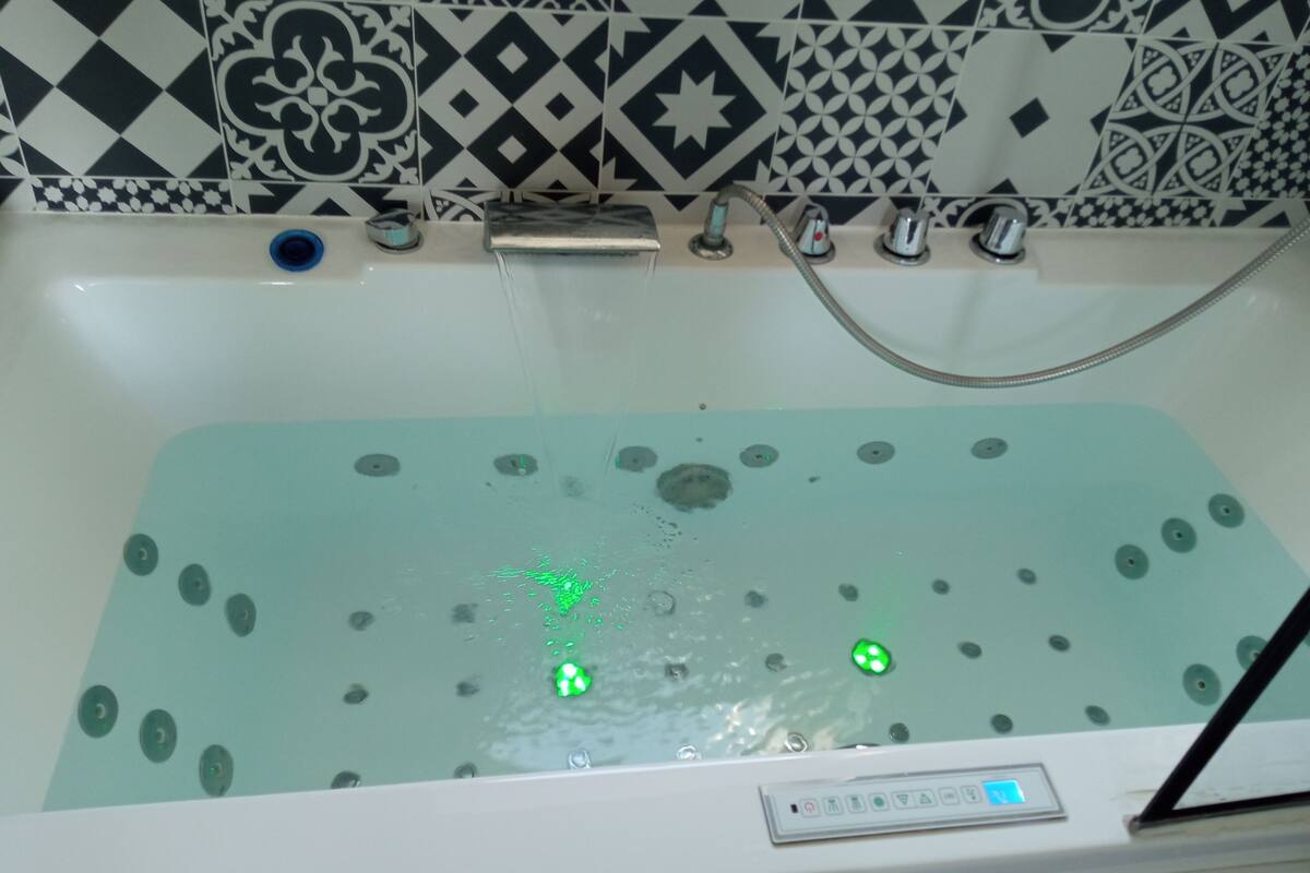 A bathtub with a control panel and a showerhead.