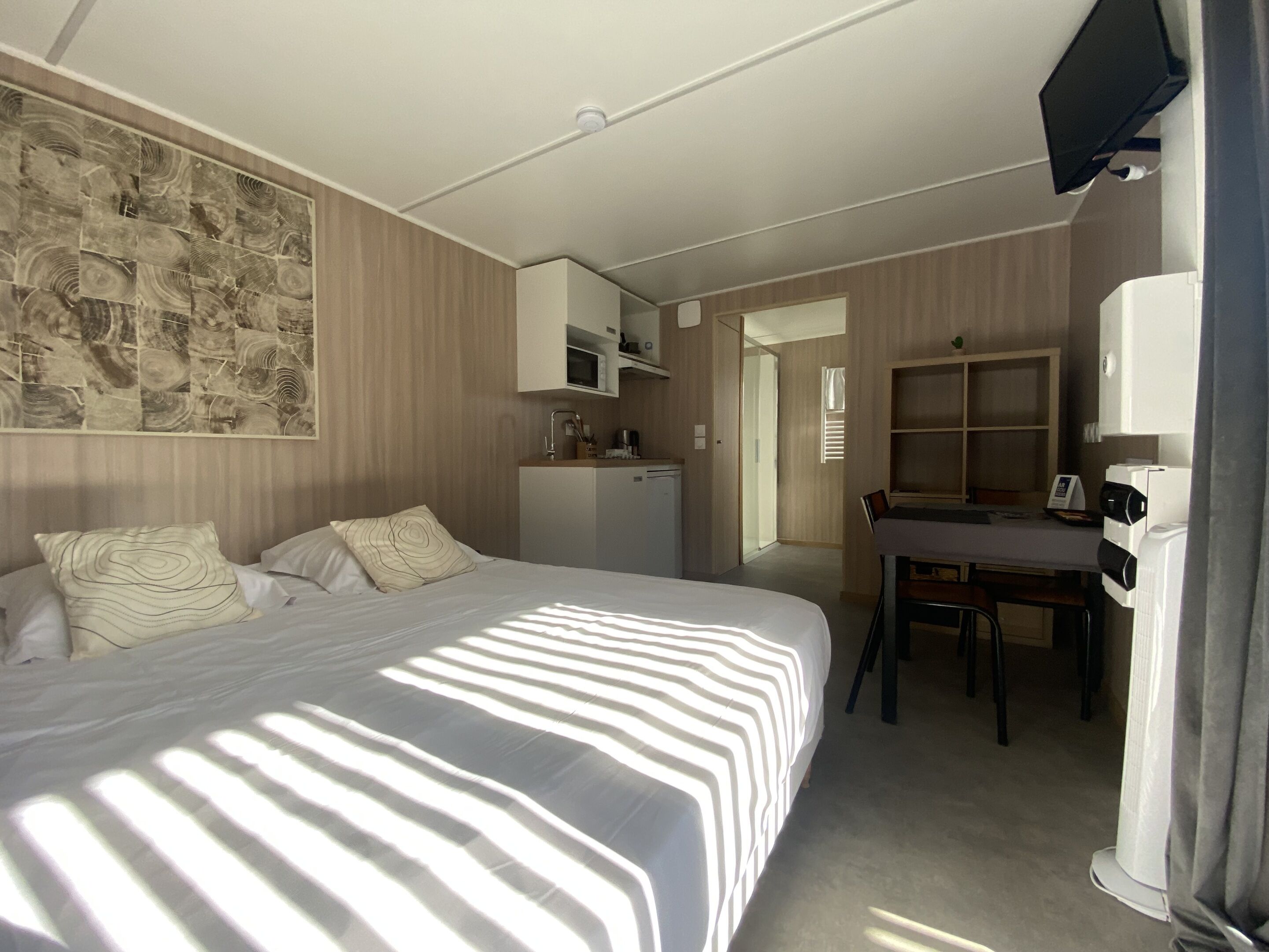 Una habitación de hotel con una cama, un escritorio, un microondas y un televisor.