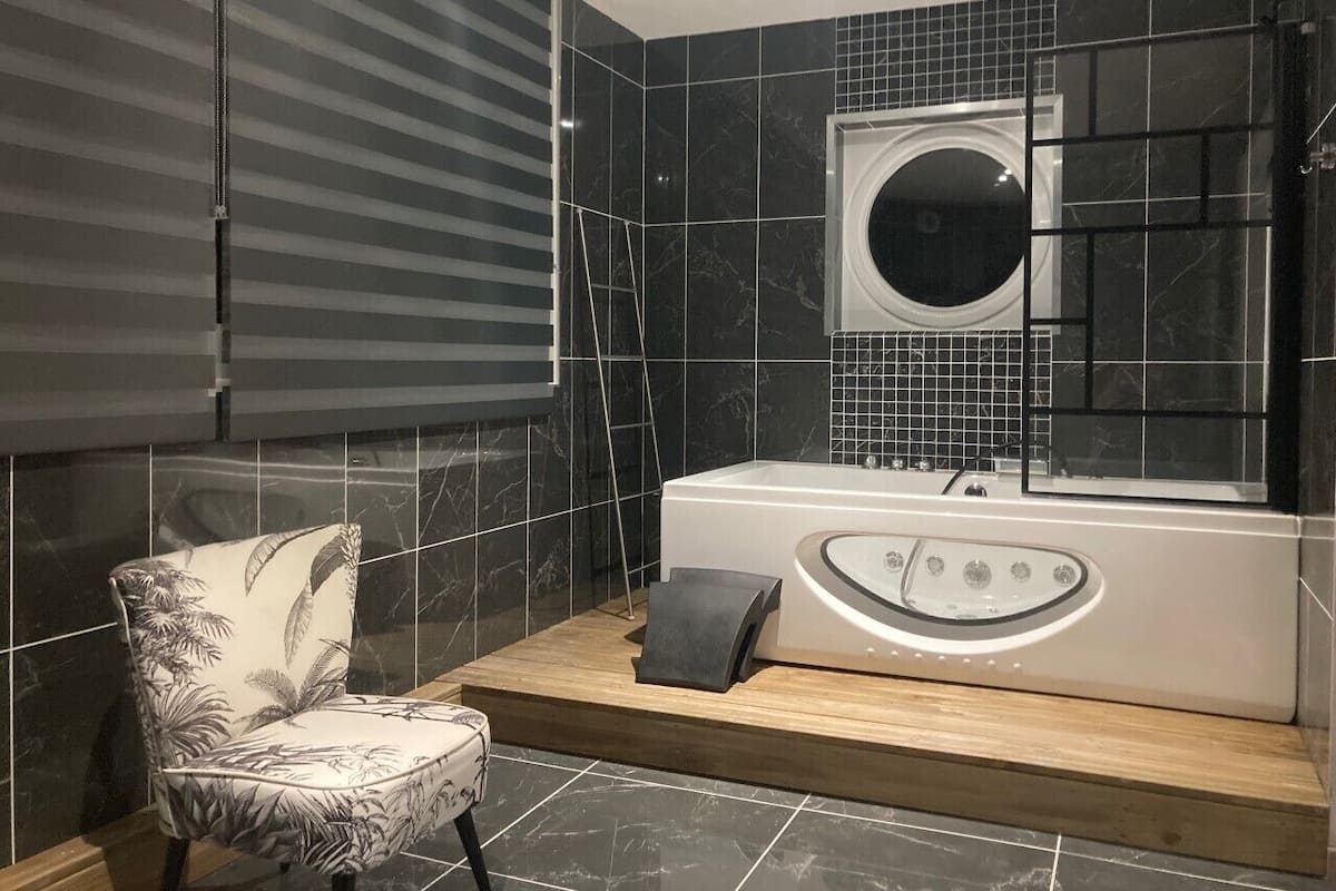 A modern bathroom with a bathtub, a shower, and a chair.