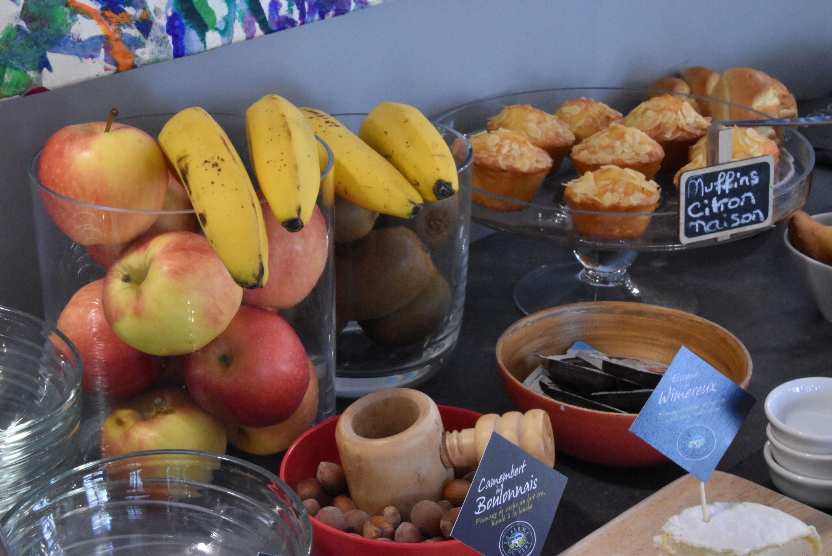 Een presentatie van etenswaren, waaronder appels, bananen, muffins en kaas.
