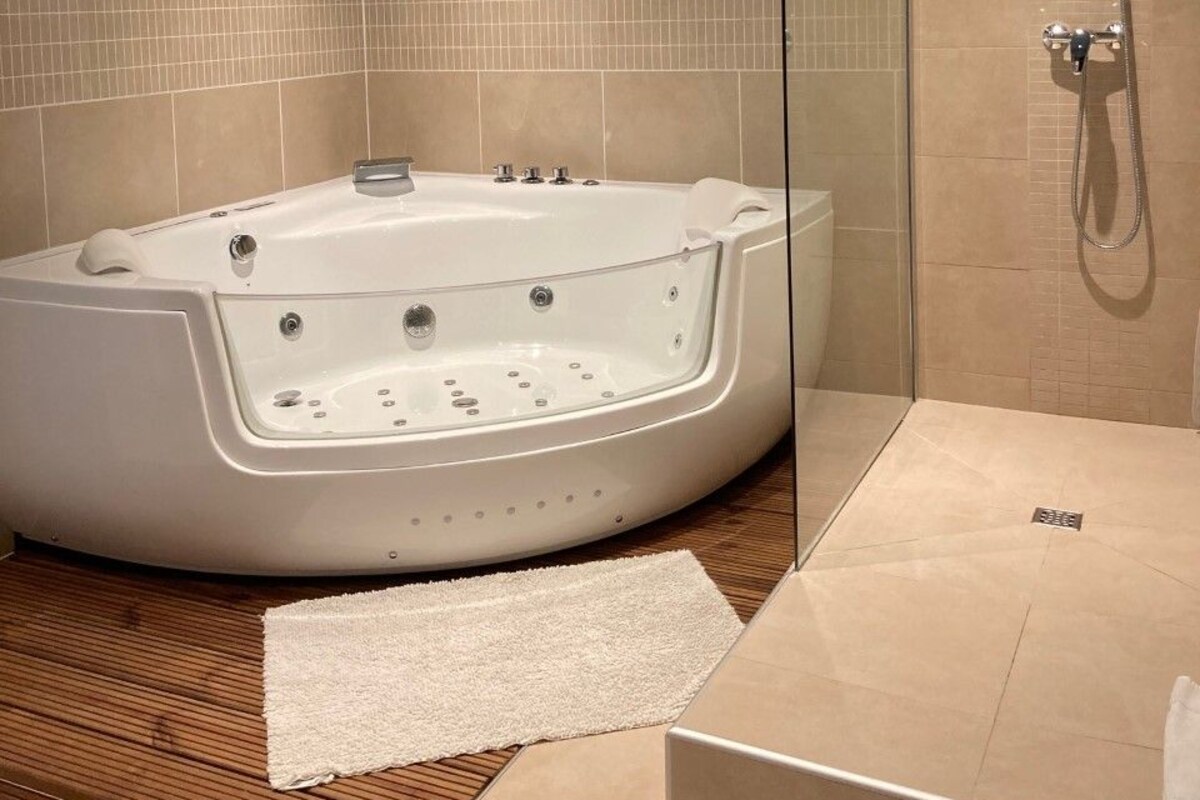 Ein modernes Badezimmer mit freistehender Badewanne, einer gläsernen Dusche und Holzboden.