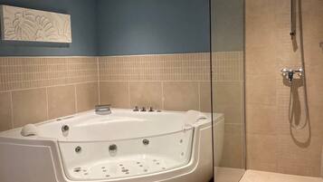 Een moderne badkamer met een vrijstaand bad, een douche met glazen wanden en een houten vloer.