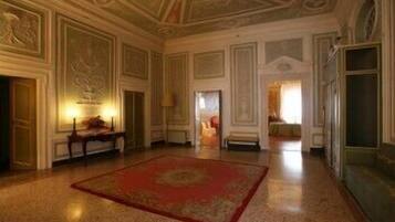 A spacious room with a red carpet, ornate ceiling, and classical architecture.