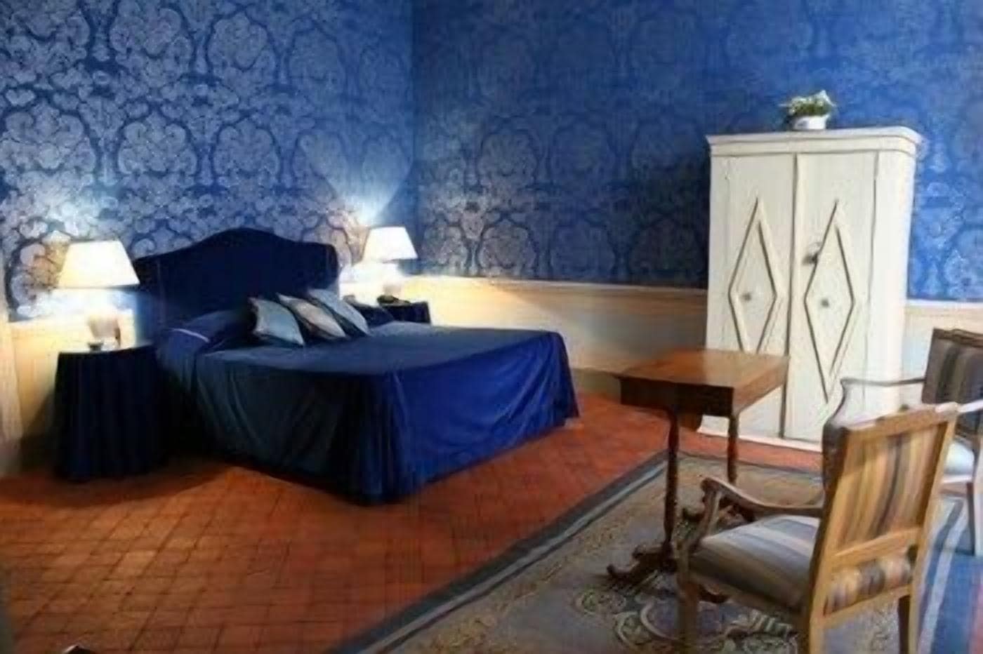 Ein Schlafzimmer mit einem Bett, zwei Nachttischen, einer Kommode und einem Sessel.