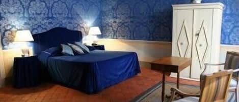 Un dormitorio con una cama, dos mesitas de noche, un tocador, un aparador y una silla.