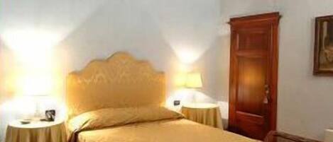 A bedroom with a large bed, two bedside lamps, a wooden chair, and a wooden wardrobe.