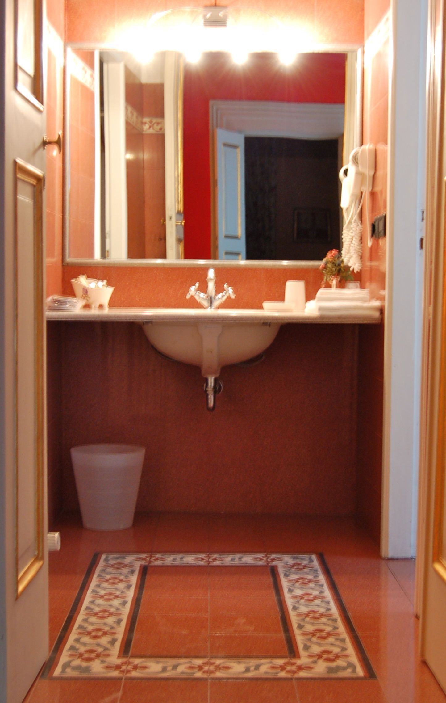 A bathroom with a sink, mirror, and a trash bin.