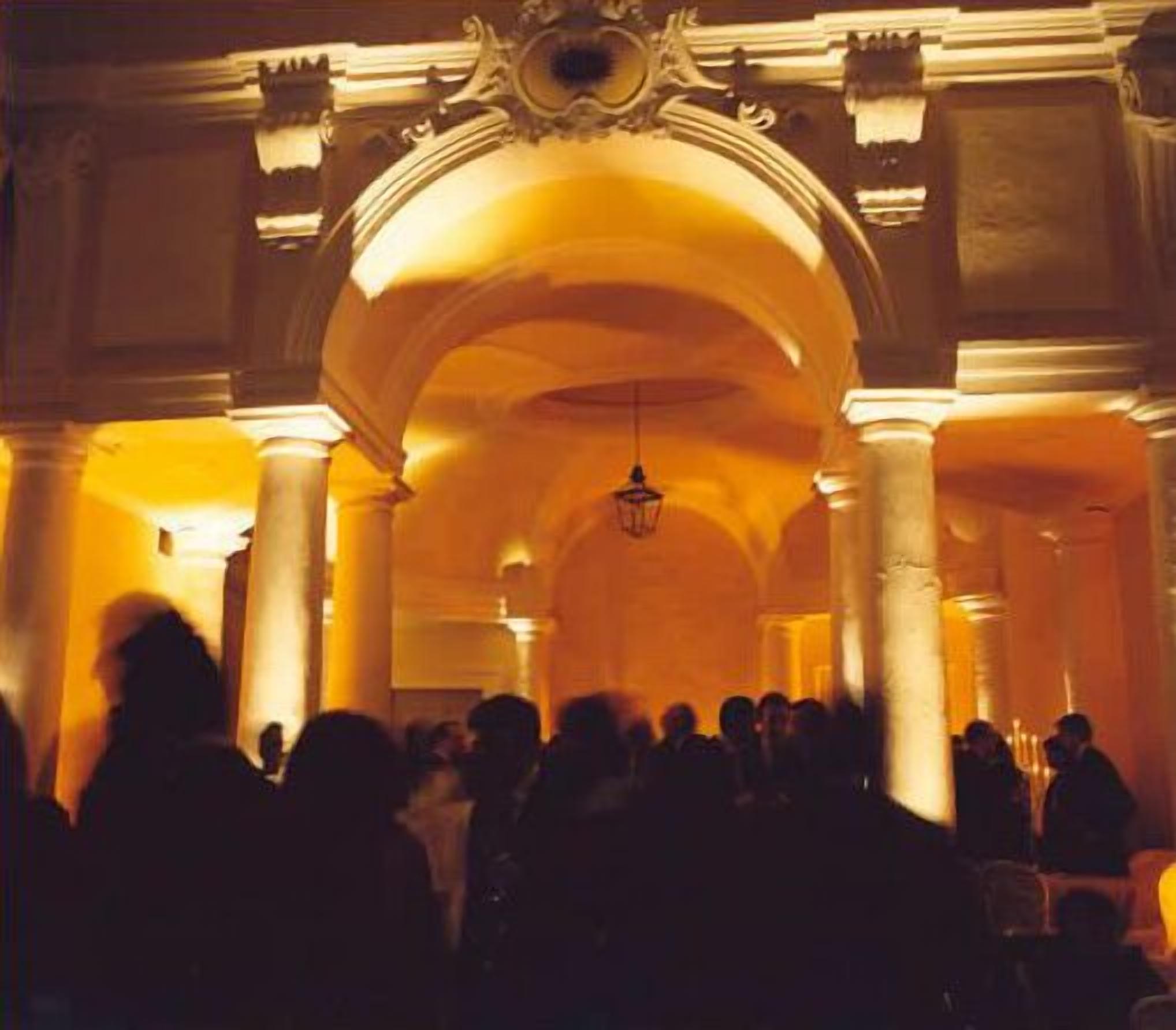 Un espace intérieur doté de hauts plafonds et d’une architecture classique, comprenant des colonnes et des arches.