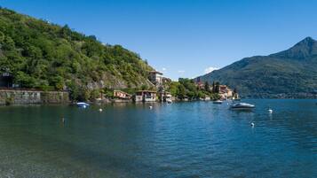 A lakeside view with boats, buildings, and a mountain.