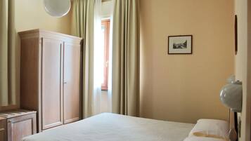 Ein Schlafzimmer mit Bett, Kleiderschrank, Nachttisch, Lampe und einem gerahmten Bild an der Wand.