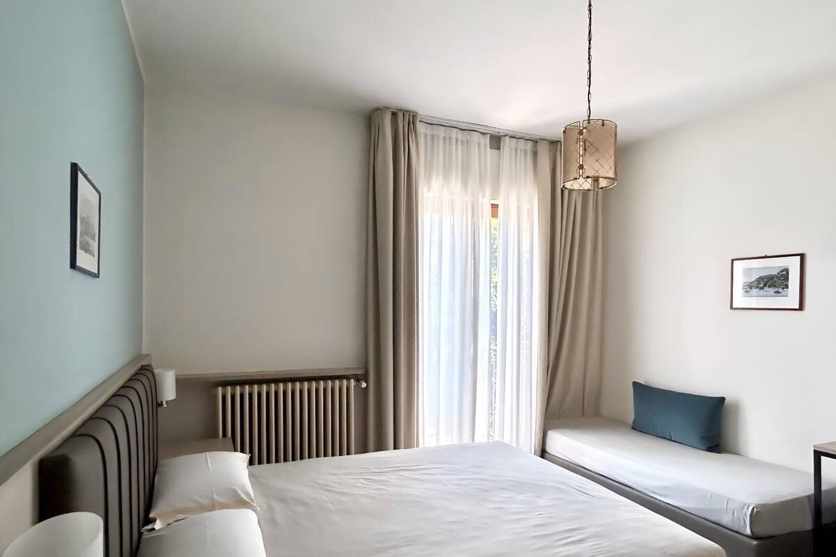Moderni hotellihuone, jossa on suuri sänky, sohva, patteri ja riippuvalaisin.