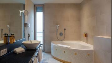 Un baño moderno con una bañera grande, un lavabo redondo y un espejo.