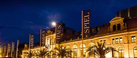 Un edificio histórico con grandes pancartas que dicen "BADEN HAUS" y "SPIEL" de noche.