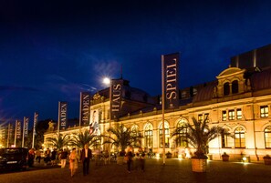 Un edificio histórico con grandes pancartas que dicen "BADEN HAUS" y "SPIEL" de noche.