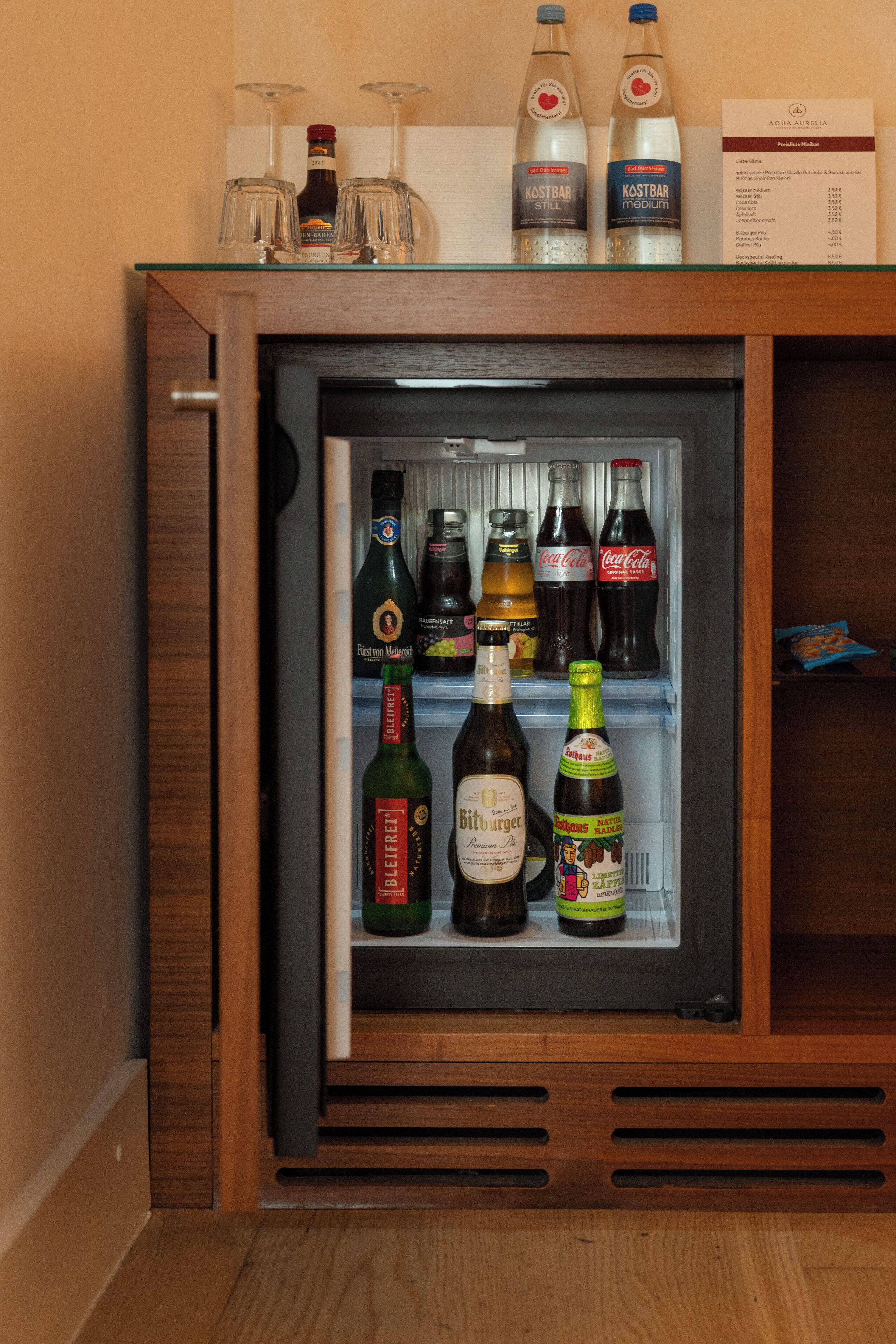 Un mini-réfrigérateur contenant une variété de boissons, notamment de la bière, du vin et des sodas.