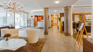 A modern hotel lobby with a chandelier, seating area, and a bar. - Aqua Aurelia Suitenhotel an den Thermen (Baden-Baden)