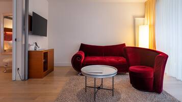 A modern living room with a red sofa, a small round table, and a TV mounted on the wall.