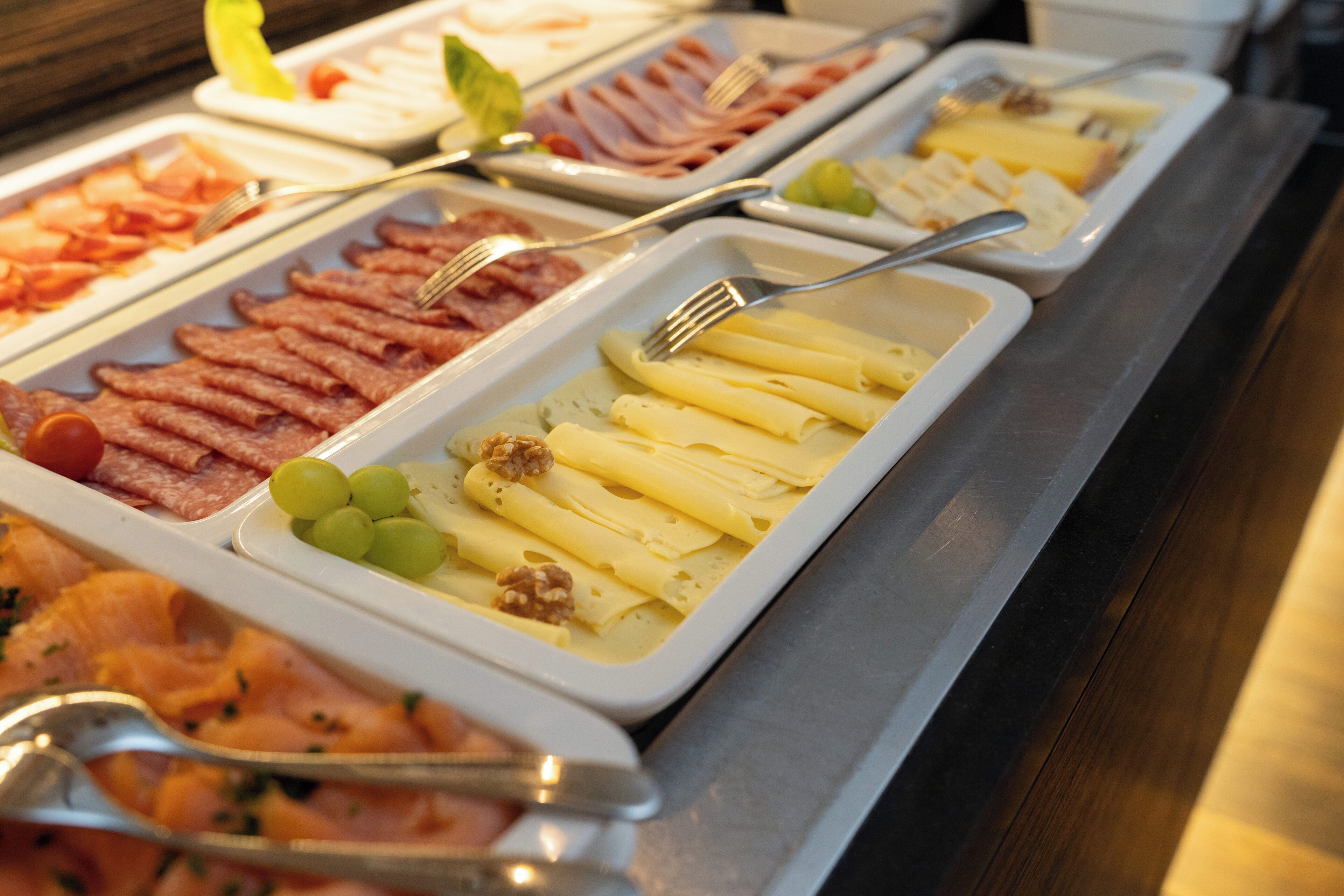A buffet with various food items including meats, cheeses, and fruits.