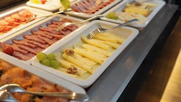 A buffet with various food items including meats, cheeses, and fruits.