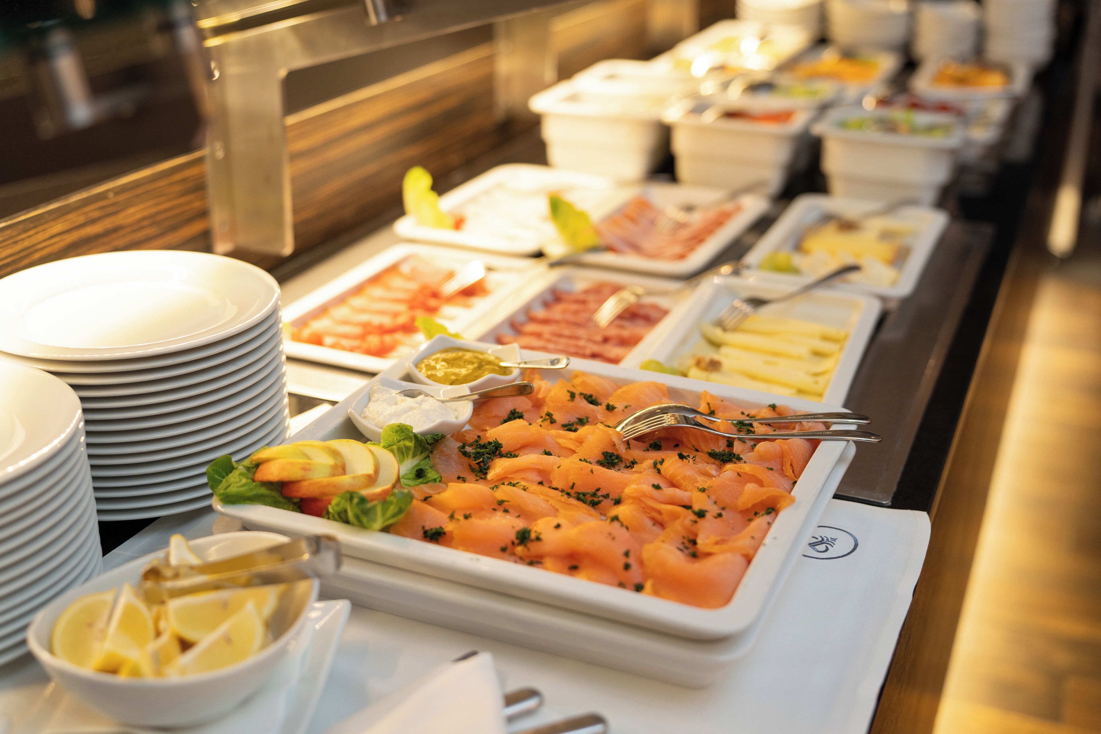 Un bufé con diversas opciones de comida, incluyendo salmón, ensaladas y otros platos.
