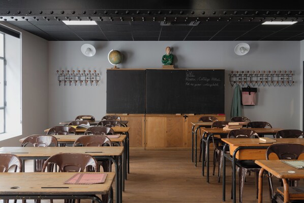 Un aula con escritorios, sillas, una pizarra y un globo terráqueo sobre un atril.