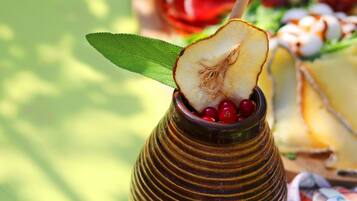 A traditional drink in a ceramic cup with a straw, garnished with a leaf and berries, on a green surface with a blurred background.