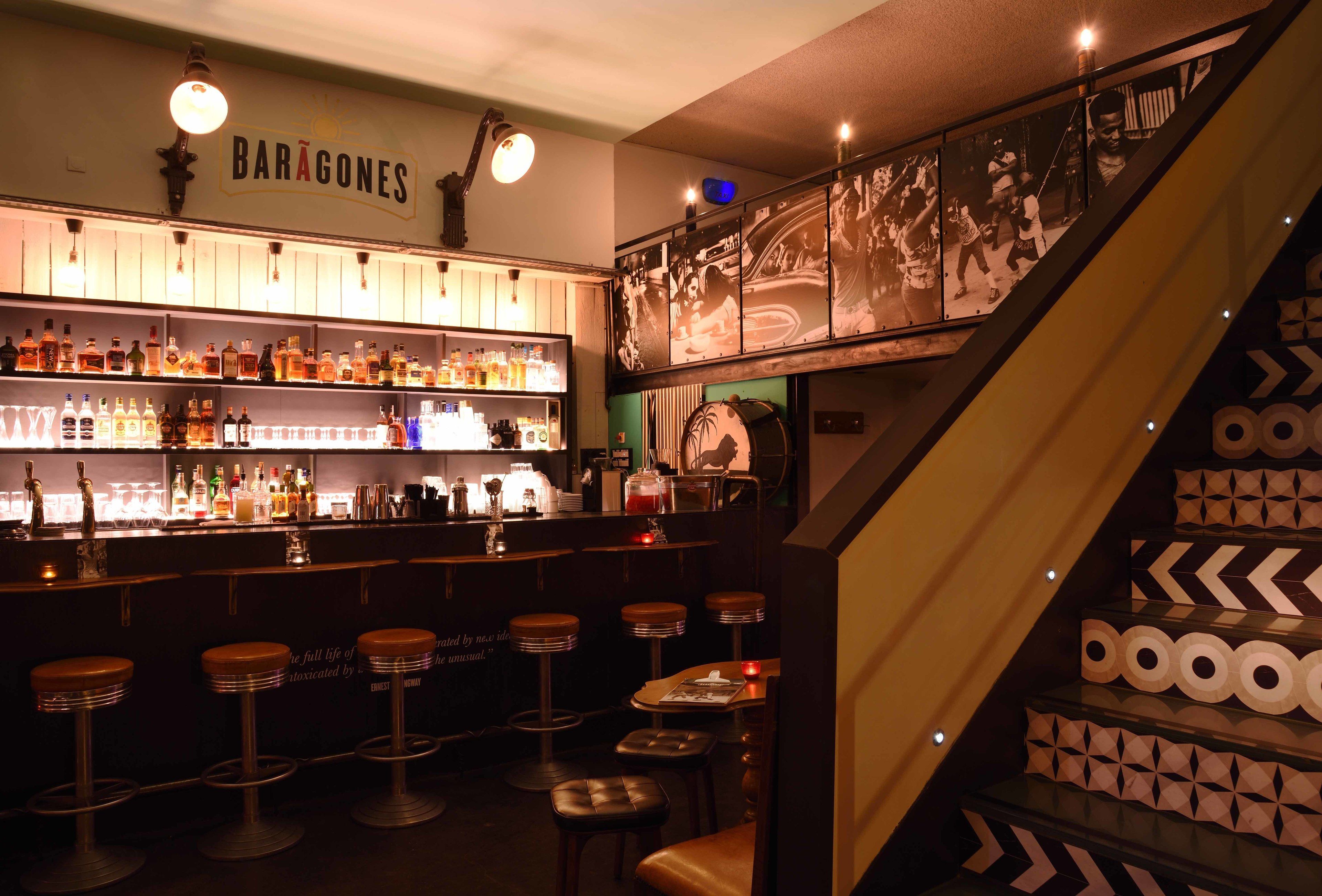 Una zona de bar con una escalera y una pared con el letrero 'BARÁGONES'.