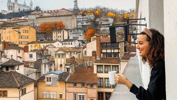 Un balcón con vistas a un paisaje urbano, que incluye edificios y una torre.