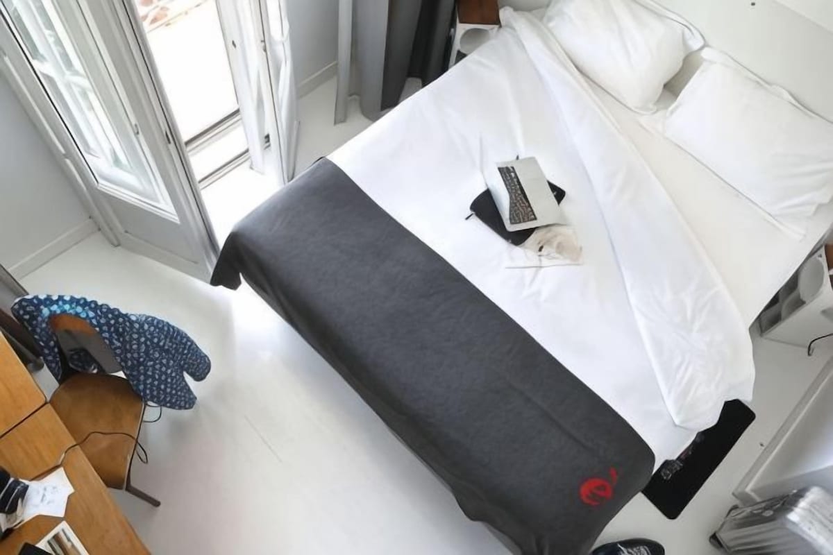 A hotel room with a bed, a desk, and a chair.
