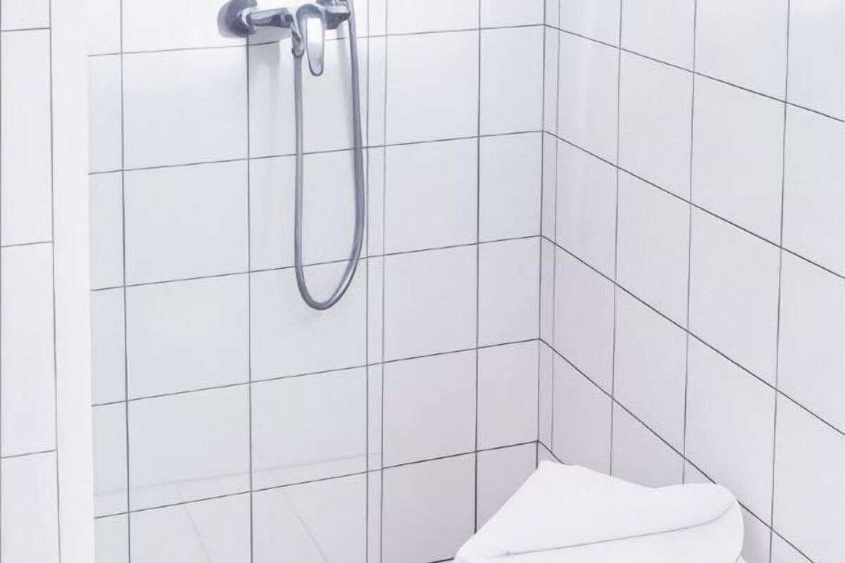A bathroom with white tiled walls and a shower.