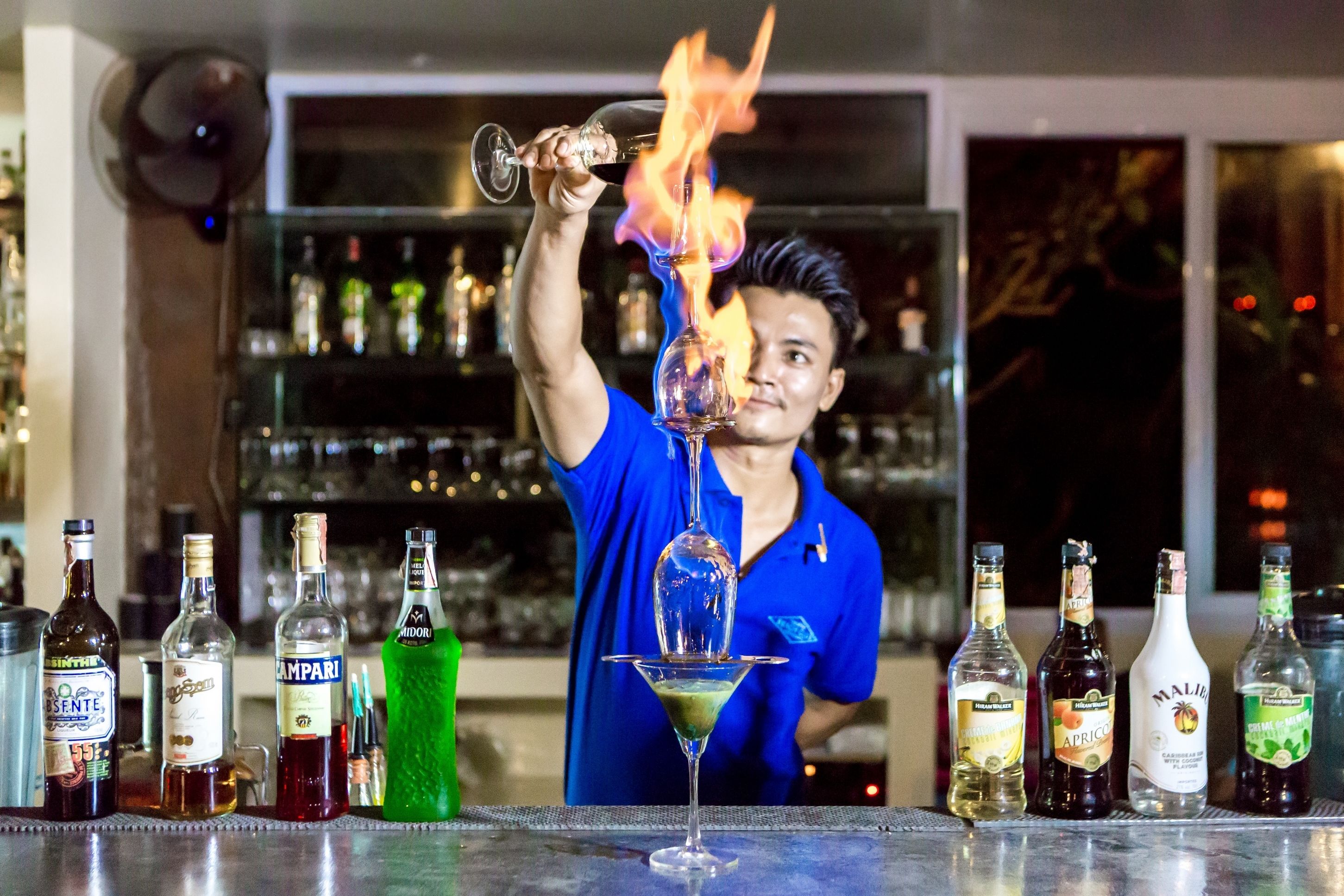 Un barman réalise une figure spectaculaire en enflammant un cocktail dans un verre.