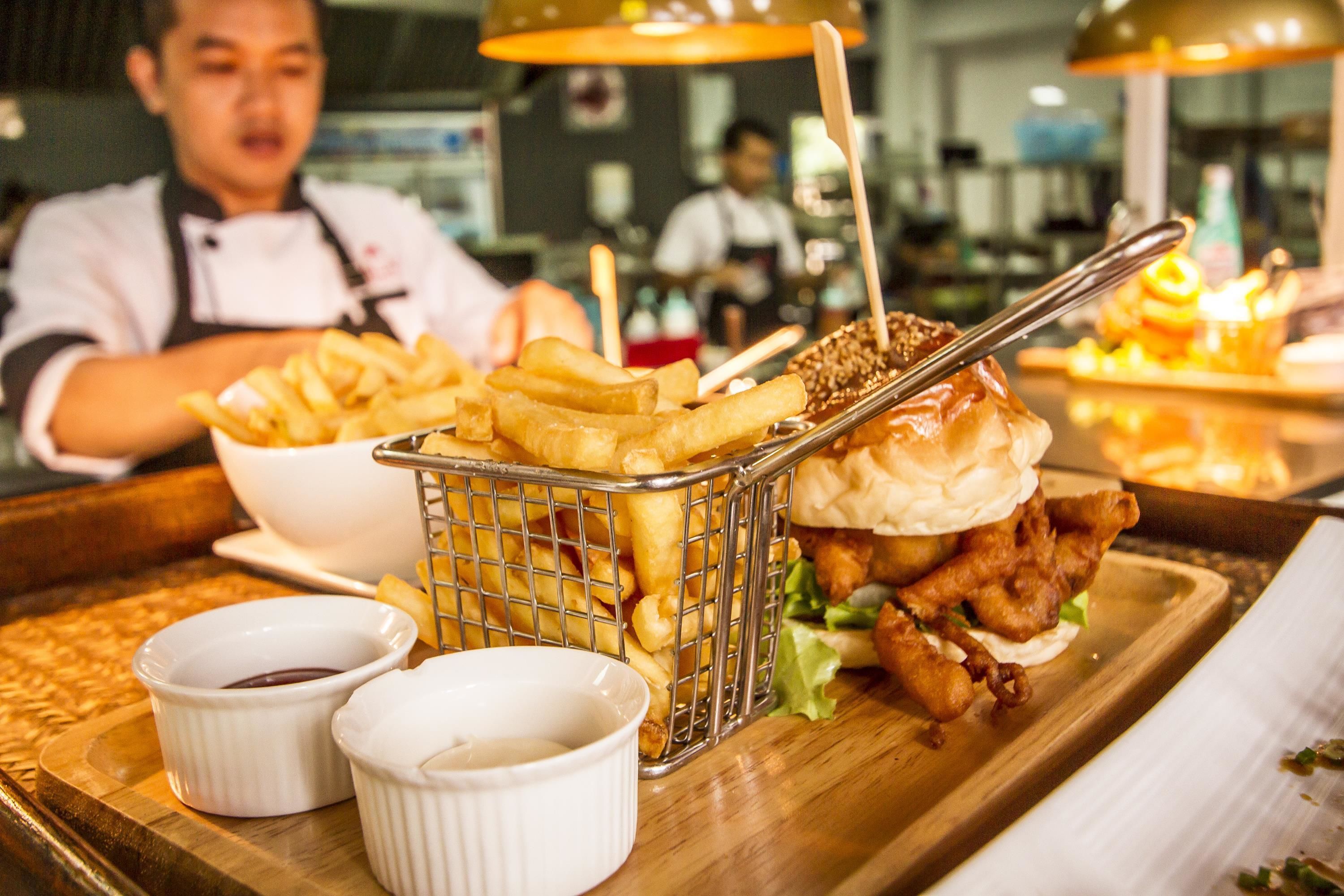 A meal tray with a burger, fries, and two dipping sauces.