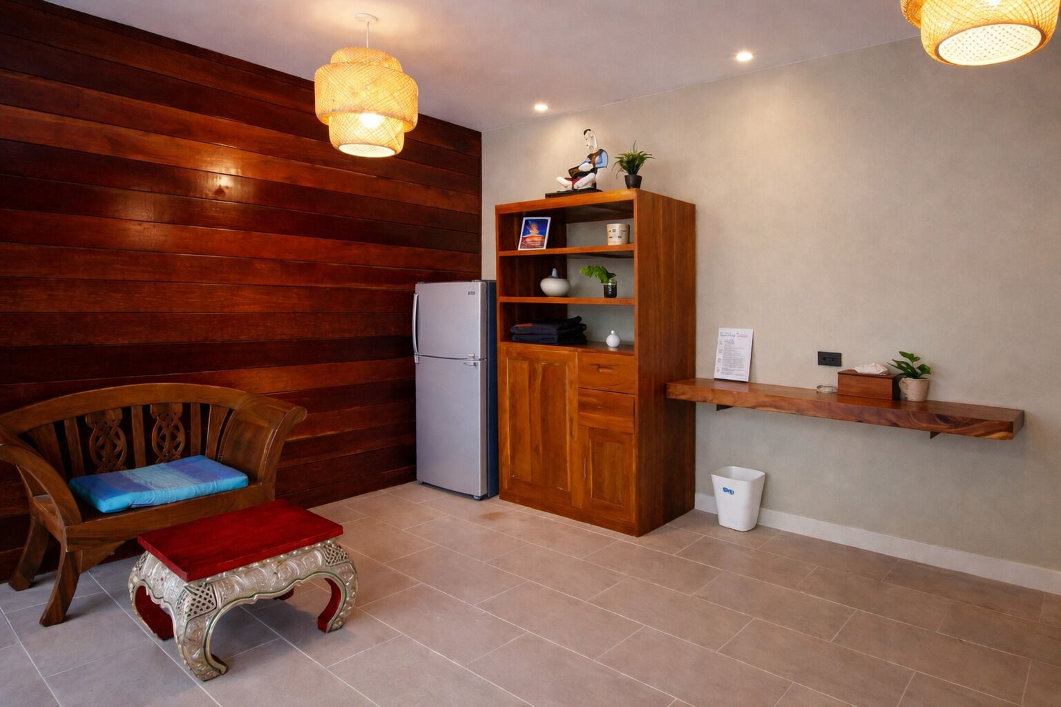 A compact kitchen with a refrigerator, wooden cabinet, and a small dining area with a chair and table.