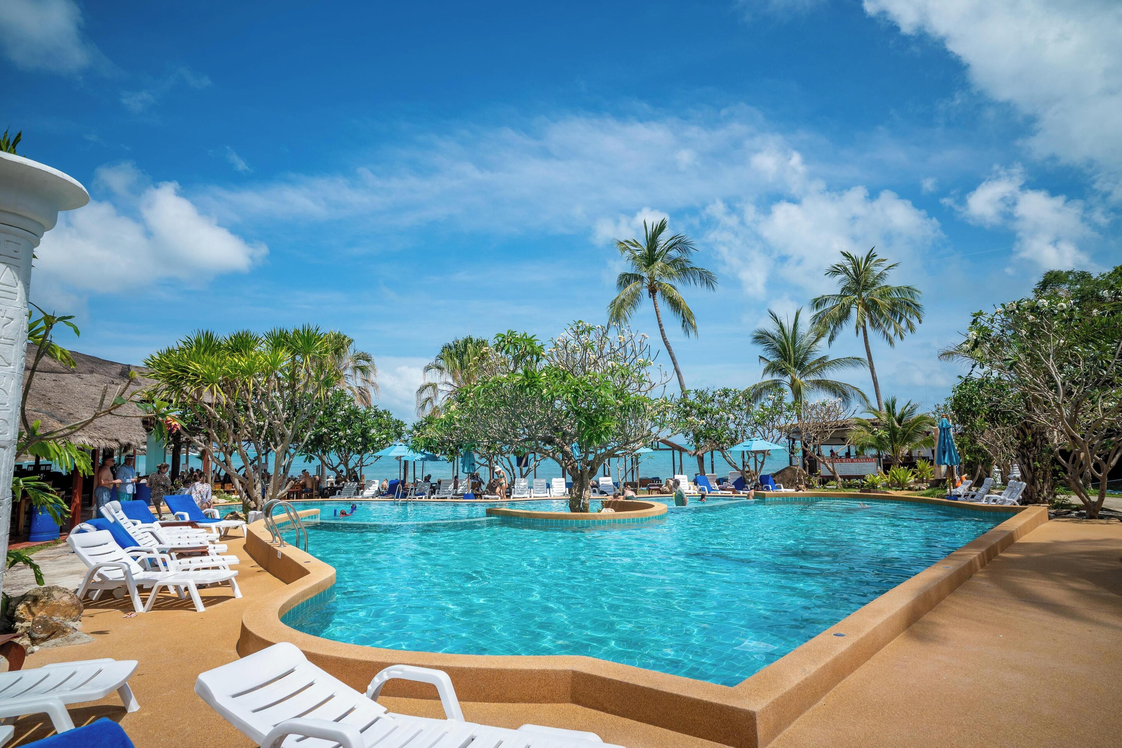 Una piscina al aire libre, sombrillas, sillones reclinables de piscina