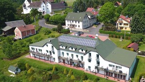 A large building with multiple balconies, a solar panel roof, and a parking area. - Seeberg (Poustka)
